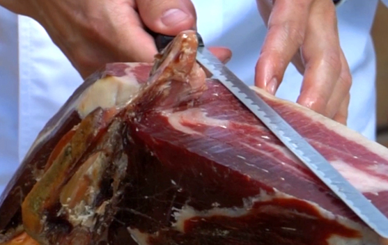 ¿Qué aspectos técnicos debo tener en cuenta al cortar un jamón en función de por dónde salga el hueso de la cadera?